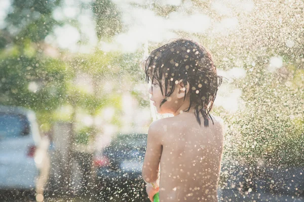 Χαριτωμένο ασιατικό αγόρι έχει τη διασκέδαση παίζοντας στο νερό από ένα σωλήνα σε εξωτερικούς χώρους — Φωτογραφία Αρχείου