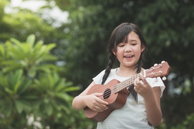 Güzel Asyalı kız oyun ukulele, 