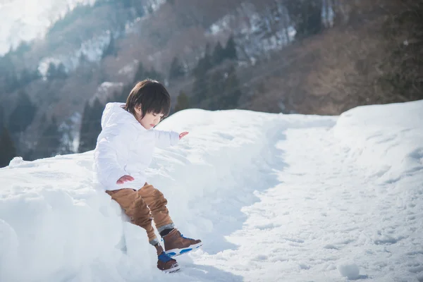Asian boy in winter clothes with snow background — Stock Photo, Image