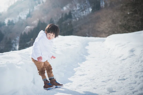 Asian boy in winter clothes with snow background — Stock Photo, Image