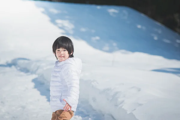 Asian boy in winter clothes with snow background — Stock Photo, Image