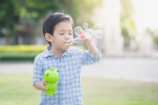 Lindo asiático niño es soplando un jabón burbuja —  Fotos de Stock
