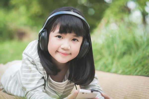 Linda menina asiática ouvindo música no parque — Fotografia de Stock