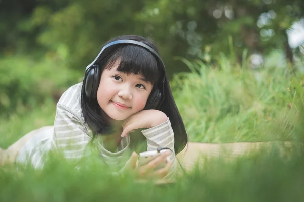 Linda menina asiática ouvindo música no parque — Fotografia de Stock