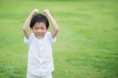 Asyalı çocuk beyaz cothes yeşil çimenlerin üzerinde oynama