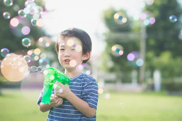 Asiatisches Kind schießt Blasen aus Blasenpistole — Stockfoto