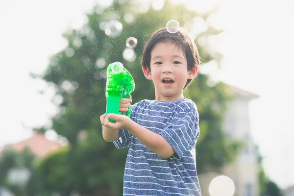 Asian child Shooting Bubbles from Bubble Gun