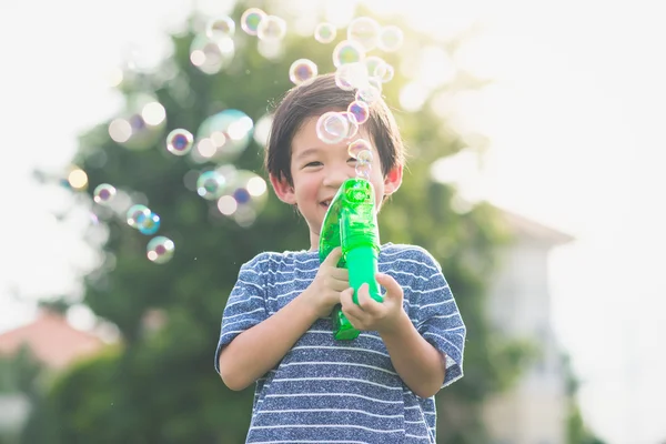 Asiatisches Kind schießt Blasen aus Blasenpistole — Stockfoto