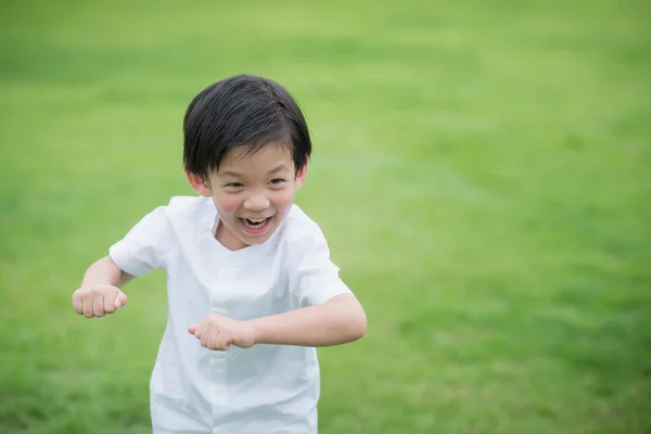 Asyalı çocuk beyaz cothes yeşil çimenlerin üzerinde oynama — Stok fotoğraf