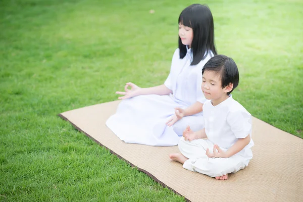 Niño asiático alimentando ciervos con vestido blanco meditando — Foto de Stock