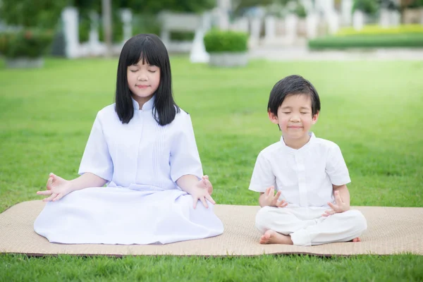 Niño asiático alimentando ciervos con vestido blanco meditando — Foto de Stock