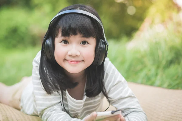 Linda menina asiática ouvindo música no parque — Fotografia de Stock