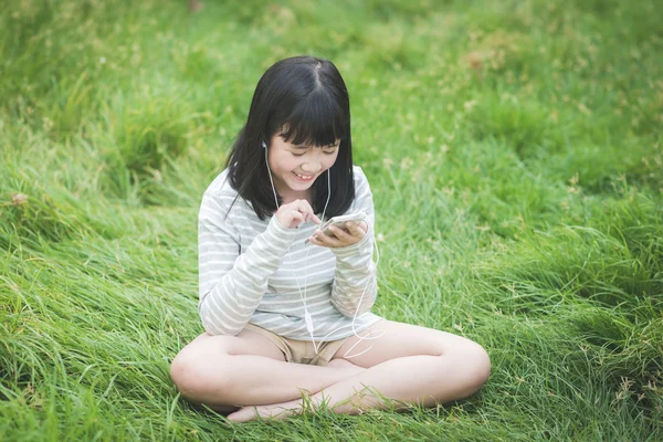 Mooi Aziatisch meisje luisteren muziek in het park — Stockfoto