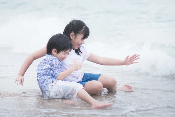 Asiatiska barn leker på stranden — Stockfoto