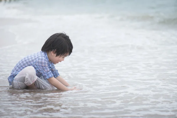 Asiatiska boy spelar på stranden — Stockfoto