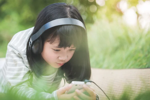 Linda menina asiática ouvindo música no parque — Fotografia de Stock