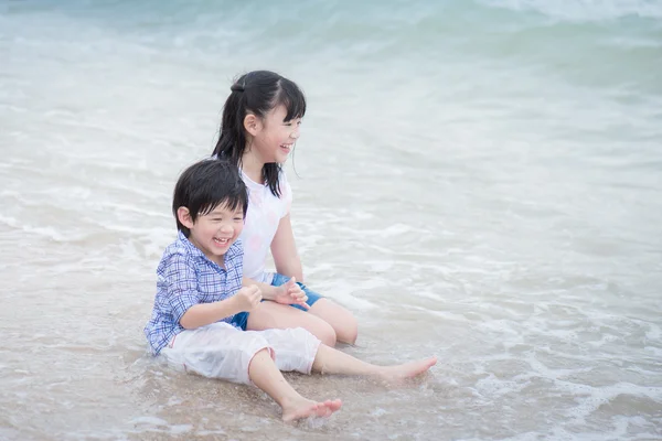 Asiatiska barn leker på stranden — Stockfoto