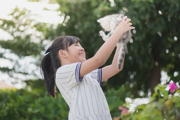 Menina asiática bonita segurando gatinho encantador com luz do sol no parque — Fotografia de Stock