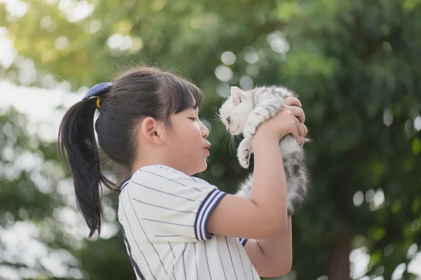Красивая азиатская девушка держит прекрасного котенка с солнцем в парке — стоковое фото