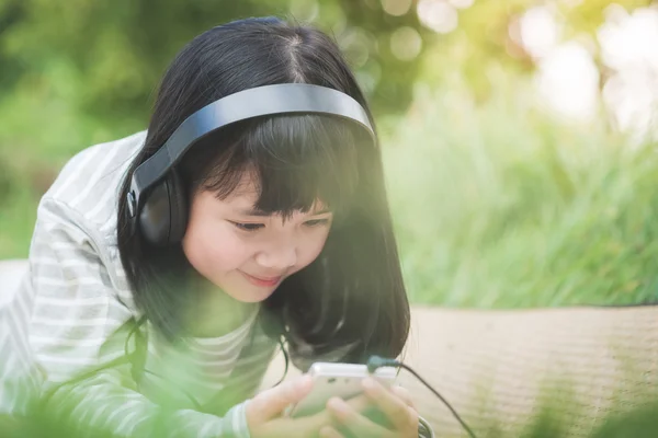 Linda menina asiática ouvindo música no parque — Fotografia de Stock