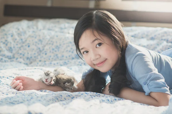Menina asiática deitada em uma cama com recém-nascido American Shorthair gatinho — Fotografia de Stock