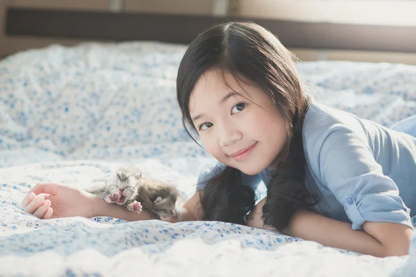 Asiatische Mädchen liegen auf einem Bett mit neugeborenen amerikanischen Kurzhaar-Kätzchen — Stockfoto