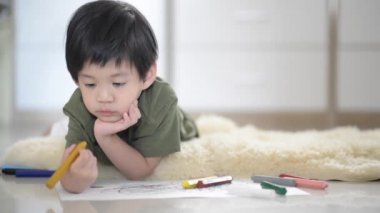 Şirin Asyalı çocuk mum boya ile resim çizim