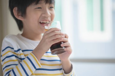 Little asian boy drinking soft drink coca cola soda