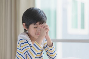 Tatlı Asyalı çocuk sabah gözleri kapalı dua ediyor.