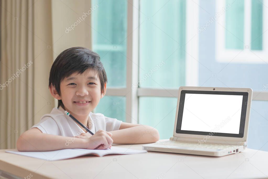 Cute Asian child learning class study online with a blank screen laptop at home .Social distancing  concept