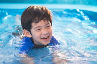 Tatlı Asyalı çocuk yüzüyor ve havuzda oynuyor.