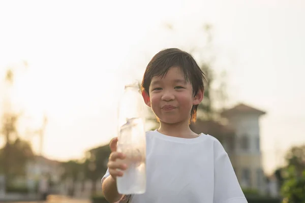 かわいいアジアの少年は屋外でボトルから水を飲む — ストック写真