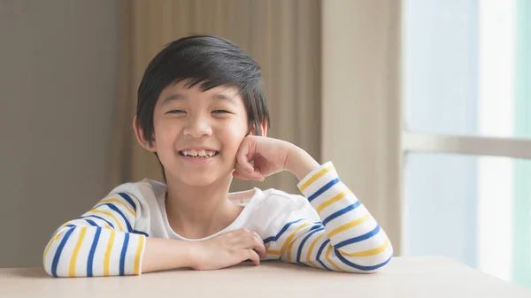 Χαριτωμένο Ασιατικό Παιδί Στηρίζεται Πηγούνια Στα Χέρια Ξύλινο Τραπέζι — Φωτογραφία Αρχείου