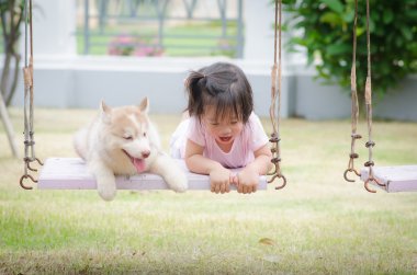 Asya bebek bebek salıncak ile köpek yavrusu üzerinde