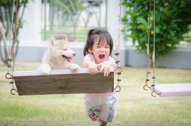 Asya bebek bebek salıncak ile köpek yavrusu üzerinde