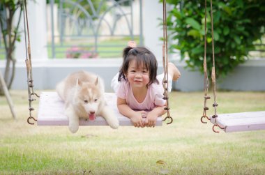 Asya bebek bebek salıncak ile köpek yavrusu üzerinde