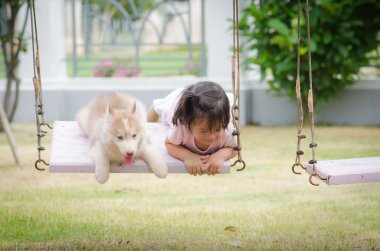 Asya bebek bebek salıncak ile köpek yavrusu üzerinde