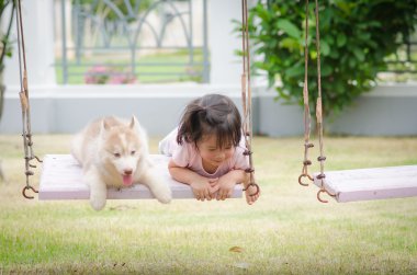 Asya bebek bebek salıncak ile köpek yavrusu üzerinde