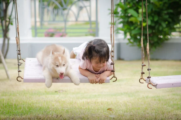 Asiático bebê no balanço com filhote de cachorro — Fotografia de Stock