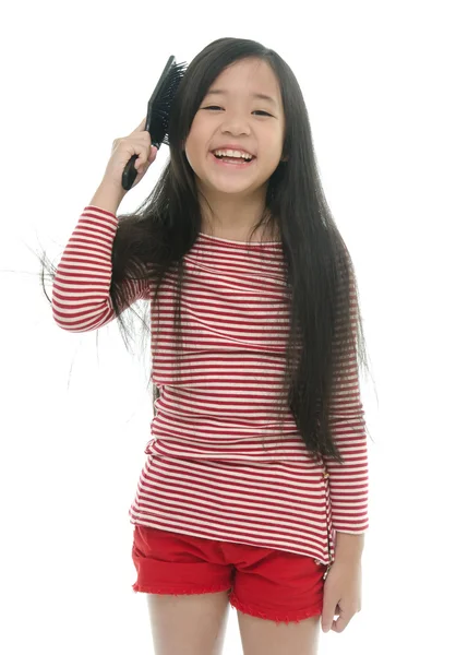 Pequeña chica asiática sonriendo y cepillando el cabello —  Fotos de Stock