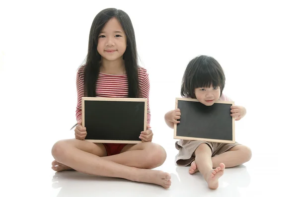 Lilla asiatiska pojke och flicka sitter och hålla svarta tavlan — Stockfoto
