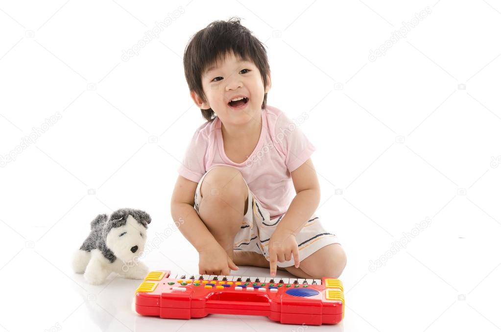 Little asian boy playing electrical toy piano 