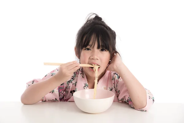 Little asian girl wearing kimono and eating noodles — Stock Photo, Image