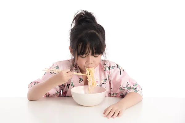 Little asian girl wearing kimono and eating noodles — Stock Photo, Image