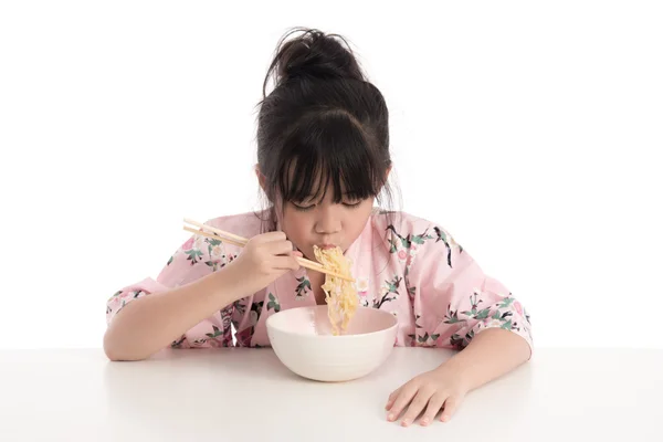 Liten asiatisk tjej iklädd kimono och äta nudlar — Stockfoto