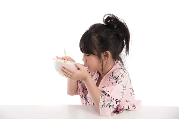 Little asian girl wearing kimono and eating noodles — Stock Photo, Image