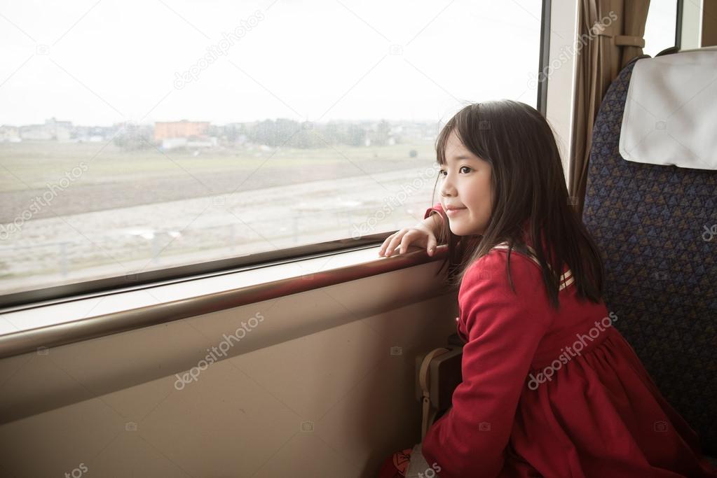 Little asian girl looking through window. 