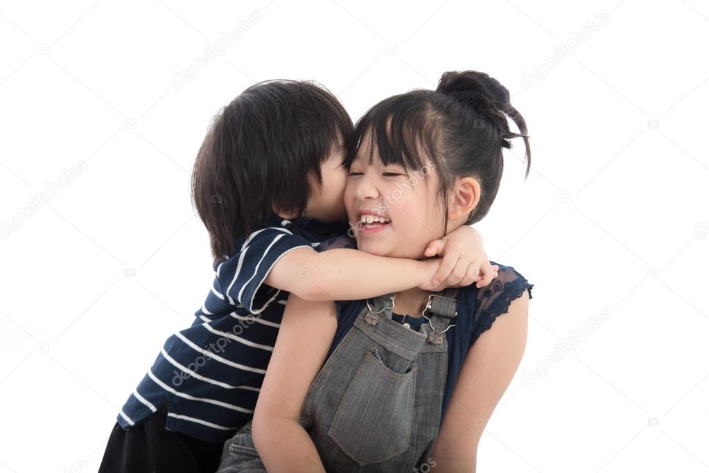 Little asian boy hugging and kissing his sister 