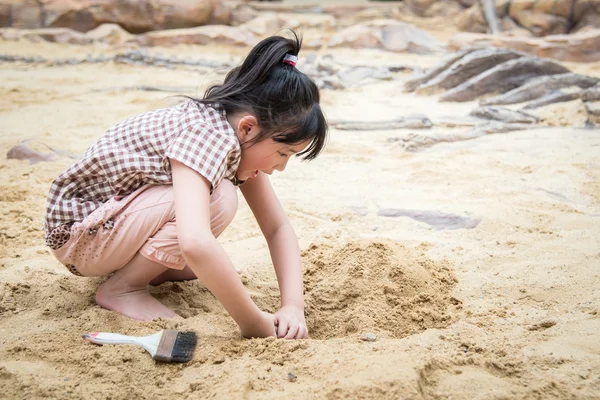 Little asian girl have fun digging in the sand