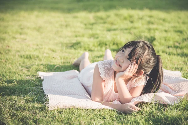 Piękna dziewczyna Azji leży i patrząc na zielonej trawie — Zdjęcie stockowe